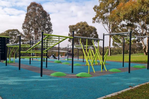 A large obstacle course with an aqua coloured astro turf surface in a bushy park setting