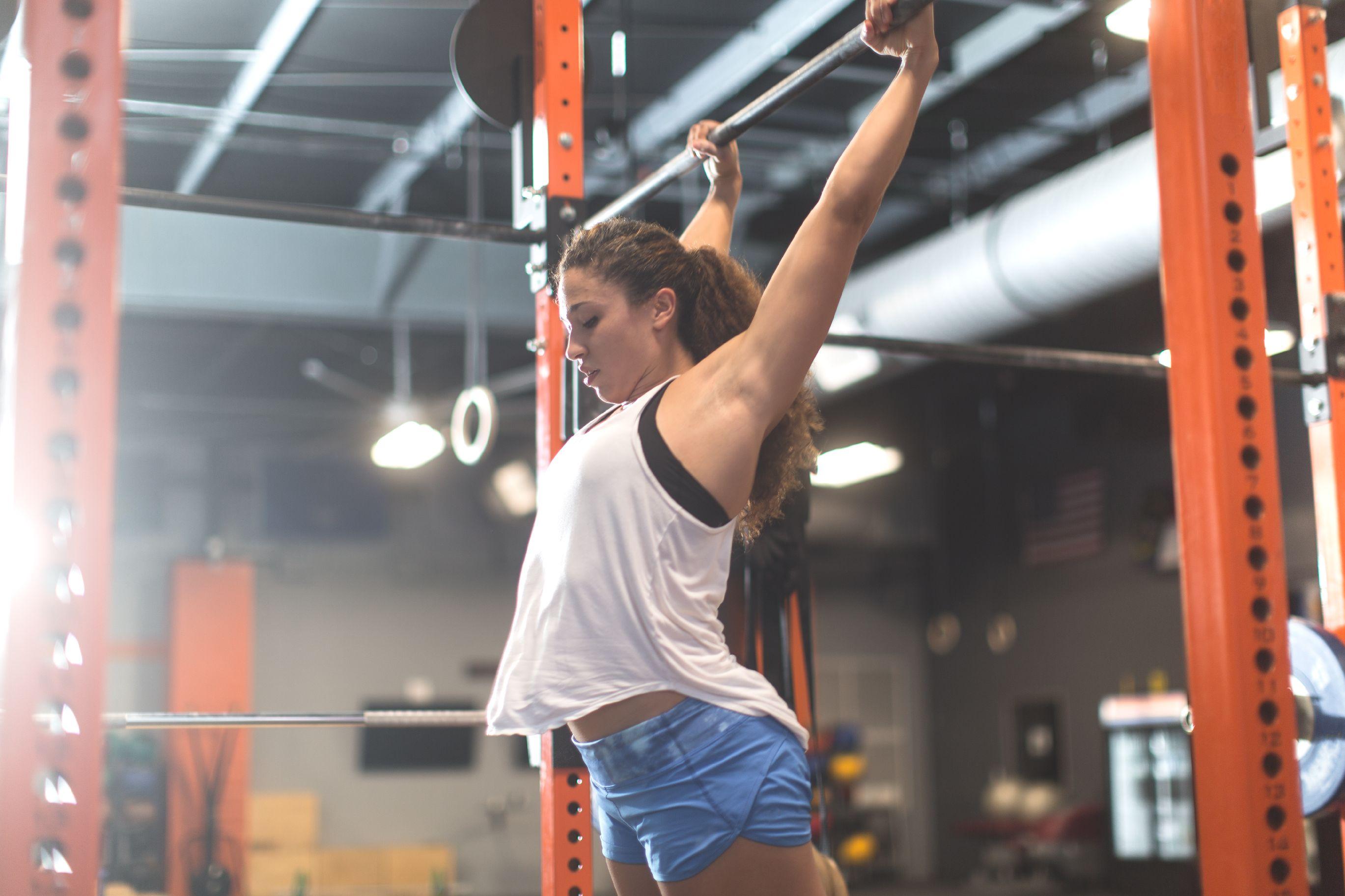 girl in white top lighting weights in a gym