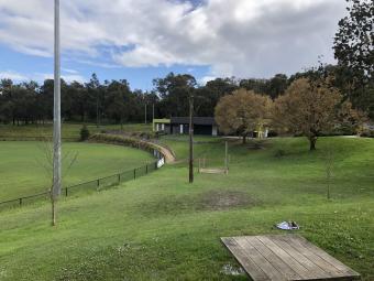 Football oval and surrounding green parkland with picnic table in foreground and club building in background